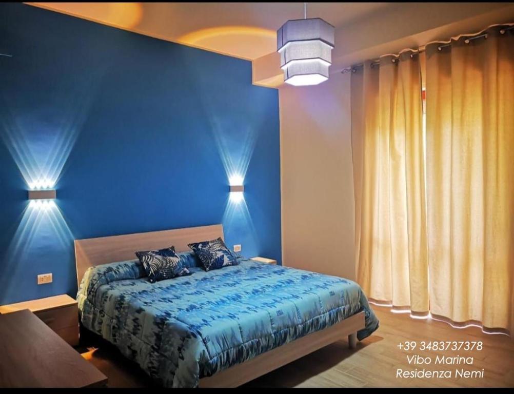 a blue bedroom with a bed and two lights at Residenza Nemi con balcone vista mare - porto in Vibo Valentia Marina