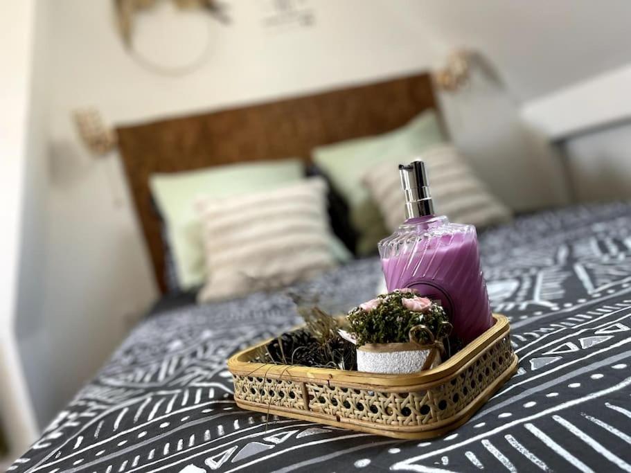 a tray with a bottle of soap and flowers on a bed at La Suite Massyl - Hypercentre & Proche Plage in Dieppe