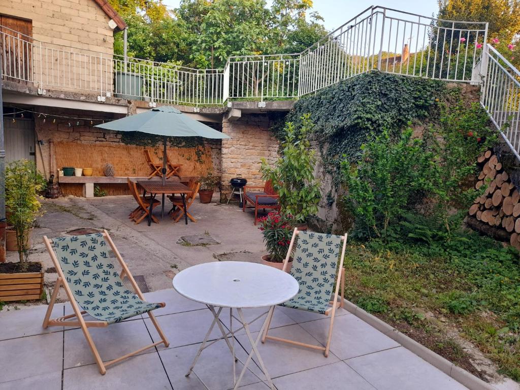 un patio avec deux chaises, une table et un parasol dans l'établissement Gîte du Bon Pays, à Frontenay