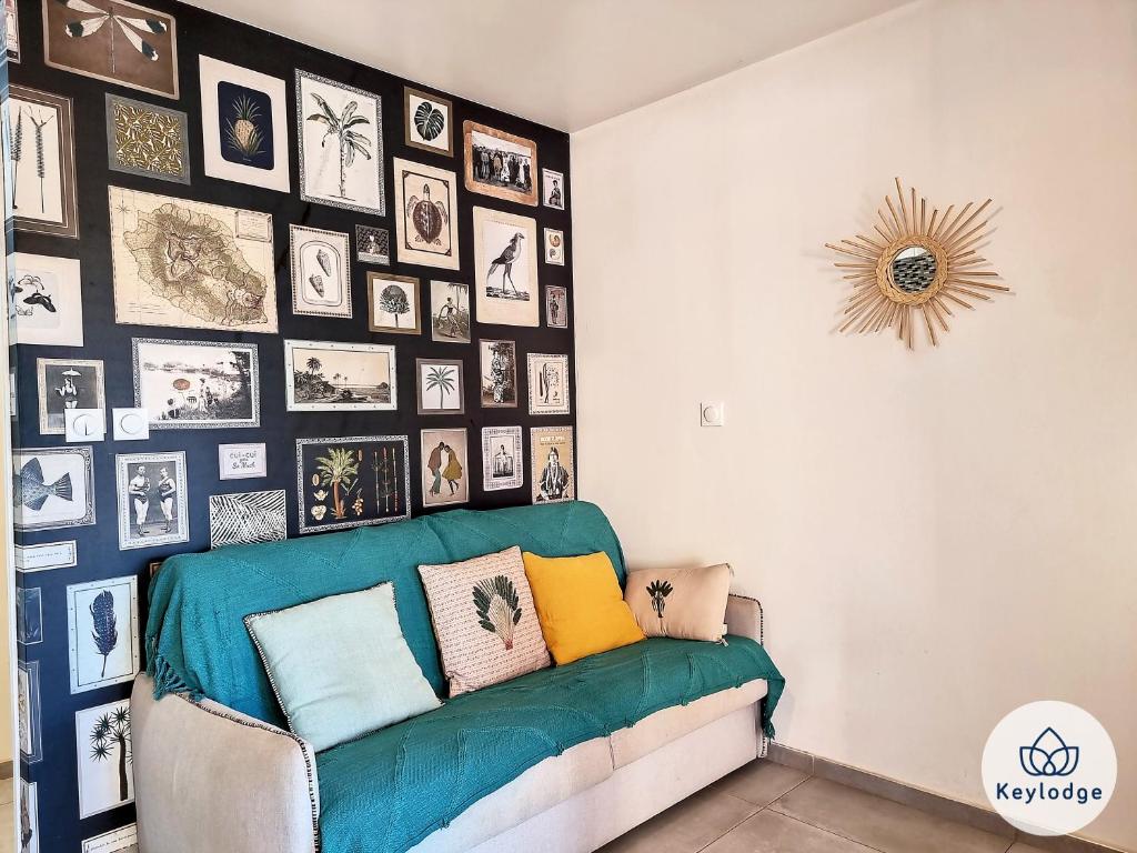 een woonkamer met een bank en een muur met foto's bij Beauté- Studio-31m2-La Saline Les Bains in La Saline Les hauts 