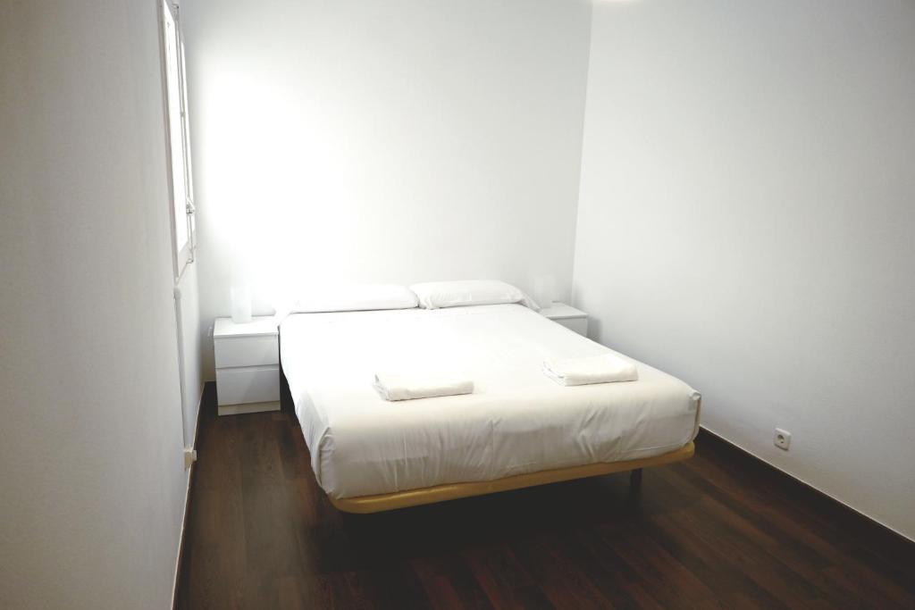 Cette petite chambre dispose d'un lit blanc et d'une fenêtre. dans l'établissement Homenfun Barcelona Park Güell, à Barcelone