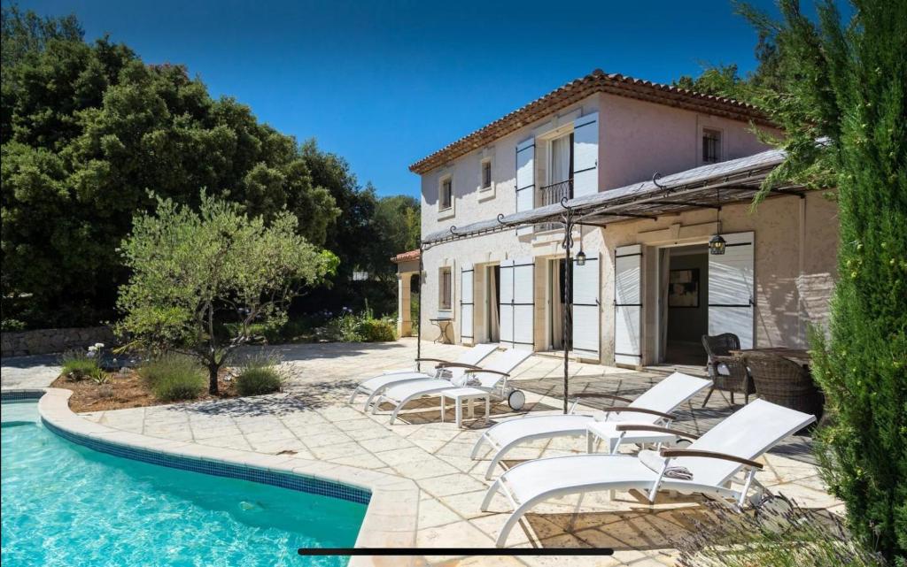 a house with chairs and a swimming pool in front of it at Stramousse in Cabris