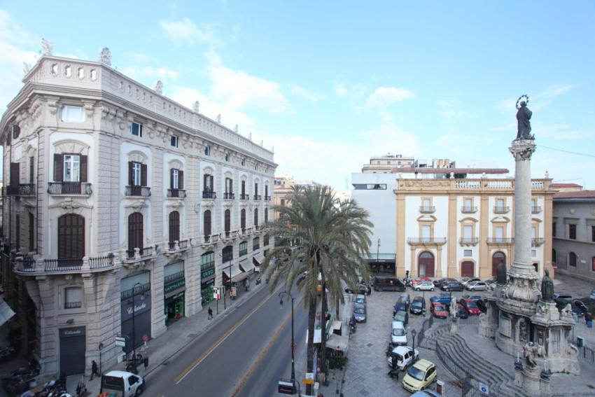 uma rua da cidade com edifícios e uma estátua num poste em Palazzo Moncada appartamento 2 em Palermo