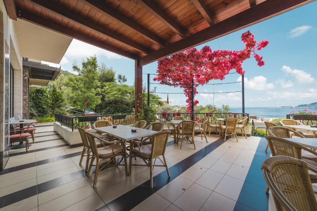a restaurant with tables and chairs on a balcony at Hotel & Apartments HEC Residence in Sveti Stefan