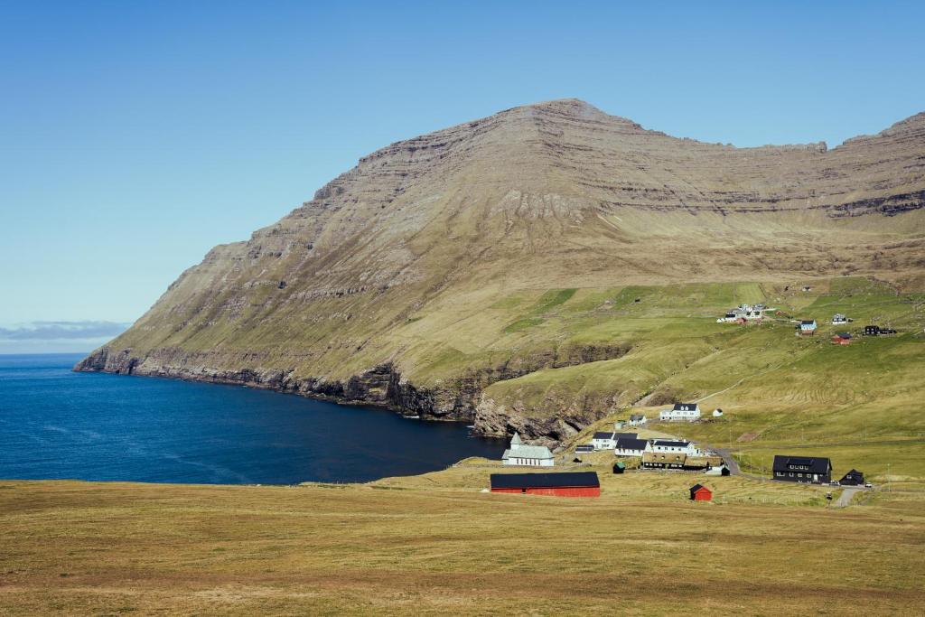 Sea and Mountain View - Scenic Village - 2BR House في Viðareiði: تل كبير بجسم كبير من الماء