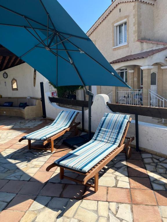 2 Liegestühle und ein Sonnenschirm auf einer Terrasse in der Unterkunft Villa Victoire 3 chambres in Venelles