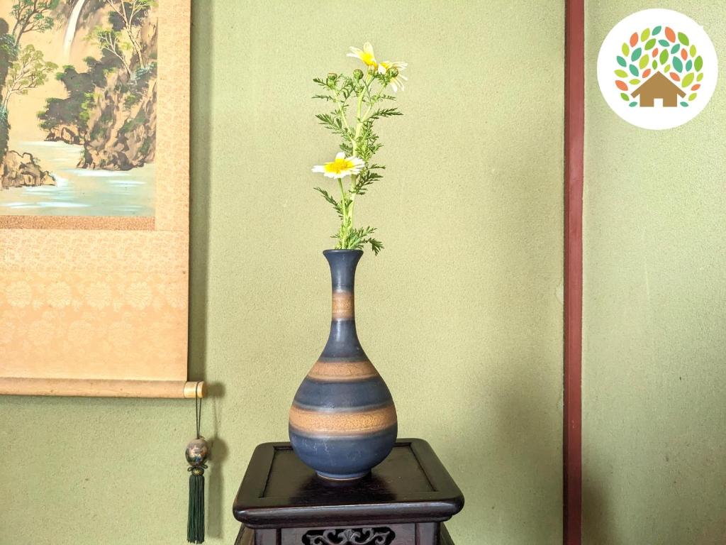 un vaso con dei fiori, seduto su un tavolo. di Farm stay inn Sanzaemon-tei 別館 2023OPEN Shiga-takasima Reserved for one group per day Japanese Old folk house a Takashima