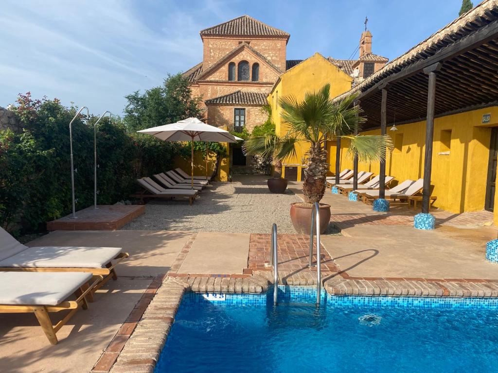 una piscina con tumbonas y un edificio con iglesia en Hotel Cortijo del Marqués, en Albolote