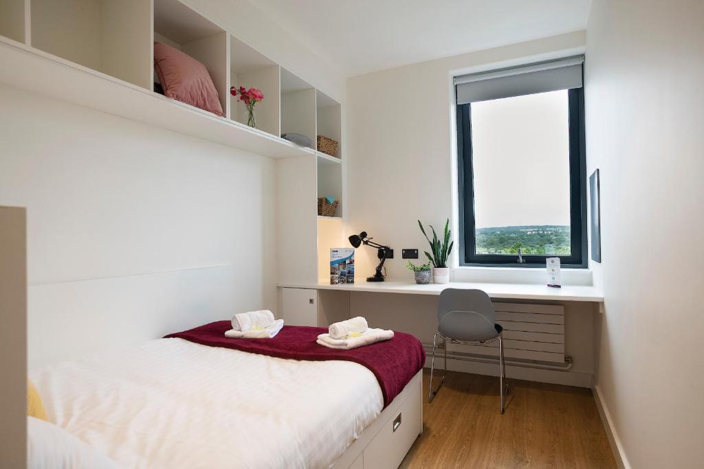 a bedroom with a bed and a desk and a window at Goldcrest Village Rooms University of Galway in Galway