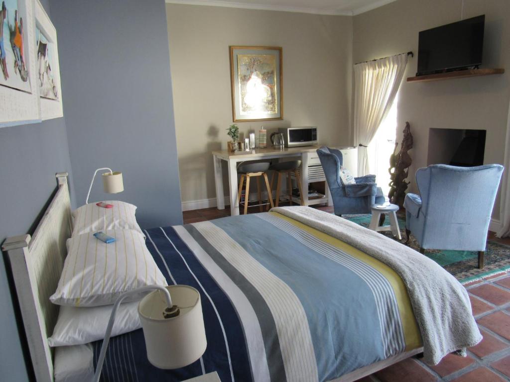 a bedroom with a bed with a desk and chairs at Omega Suite in Gansbaai