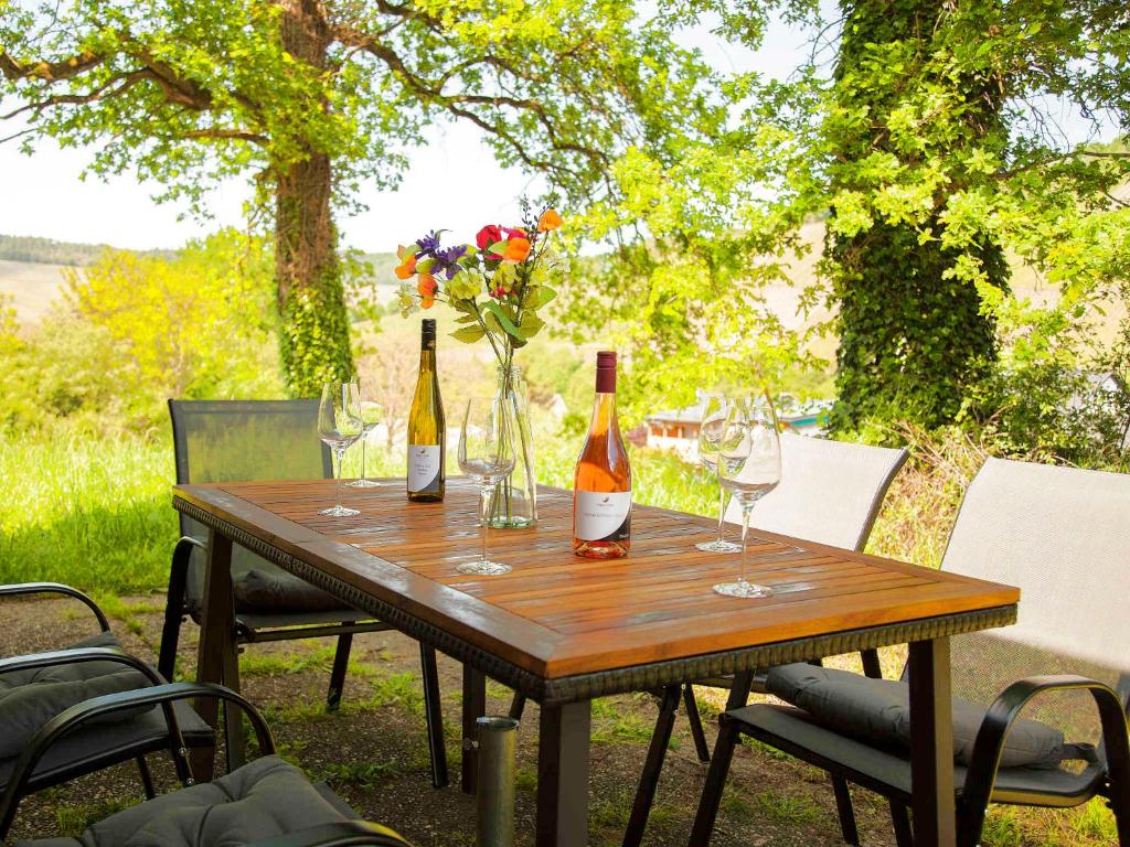 - une table en bois avec 2 bouteilles de vin et des verres dans l'établissement Ferienhaus Maring, à Maring-Noviand