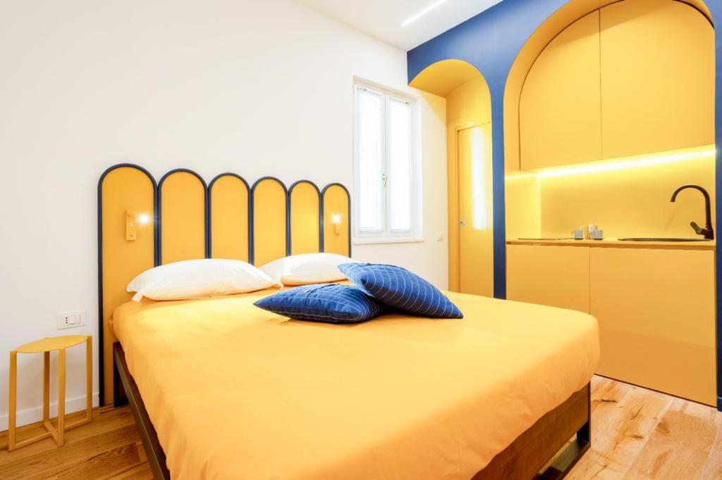 - une chambre avec un grand lit jaune et des oreillers bleus dans l'établissement Archi Rooms Boutique, à Salerne