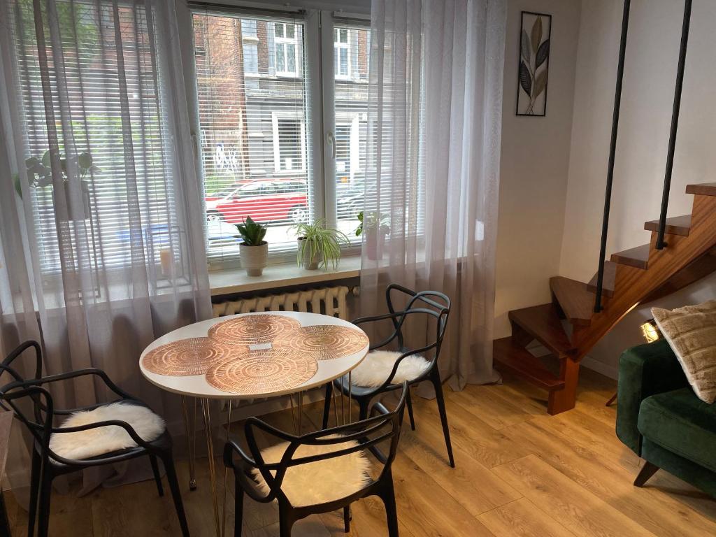 salon ze stołem i krzesłami oraz oknem w obiekcie Apartament Schodami do Nieba w Bytomiu