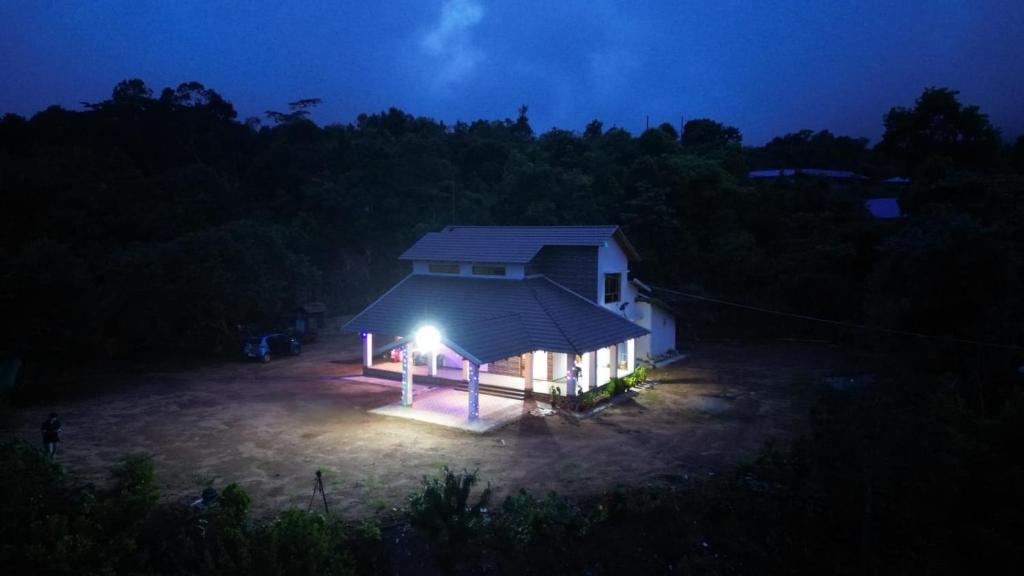 a small house with a lit up roof at night at Thotadagadde Home stay in Mudigere