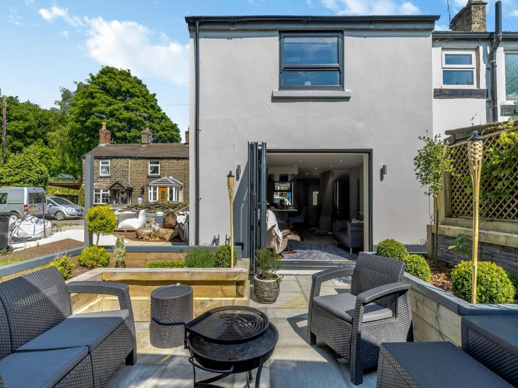 une terrasse avec des chaises et une table ainsi qu'une maison dans l'établissement Squirrel Cottage, à Glossop