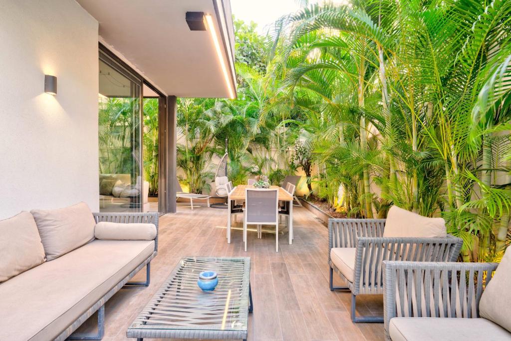 un patio con sofás, mesas y palmeras en Tranquil 2BR GardenOasis near the Sea by HolyGuest, en Tel Aviv
