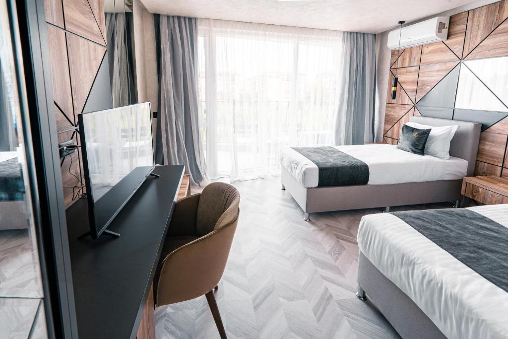 a hotel room with two beds and a desk at хотел ADDRESS in Ravda