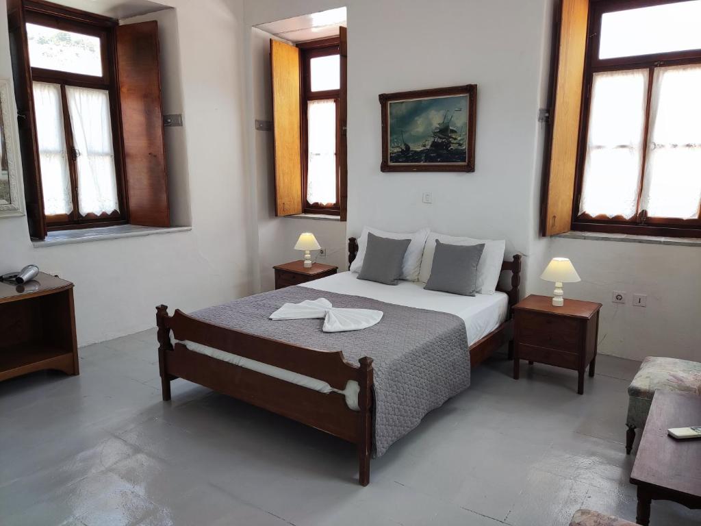 una camera da letto con un letto con due tavoli e due finestre di Achilleas Apartment a Hydra