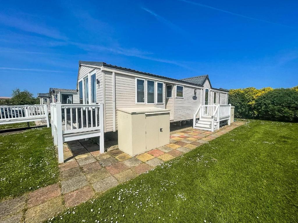 uma pequena casa com um deque e um quintal em Lovely 8 Berth Caravan At Hopton Holiday Park To Hire In Norfolk Ref 80017l em Great Yarmouth