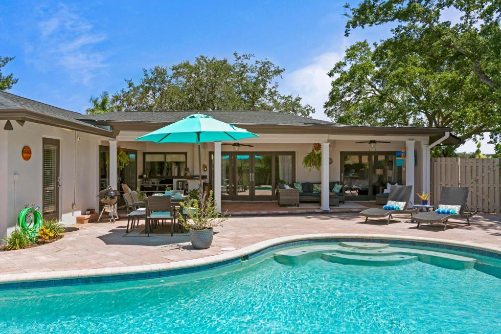 a swimming pool with an umbrella next to a house at Saltwater & Sun Pool / Fire Pit / Family Arcade in Tampa