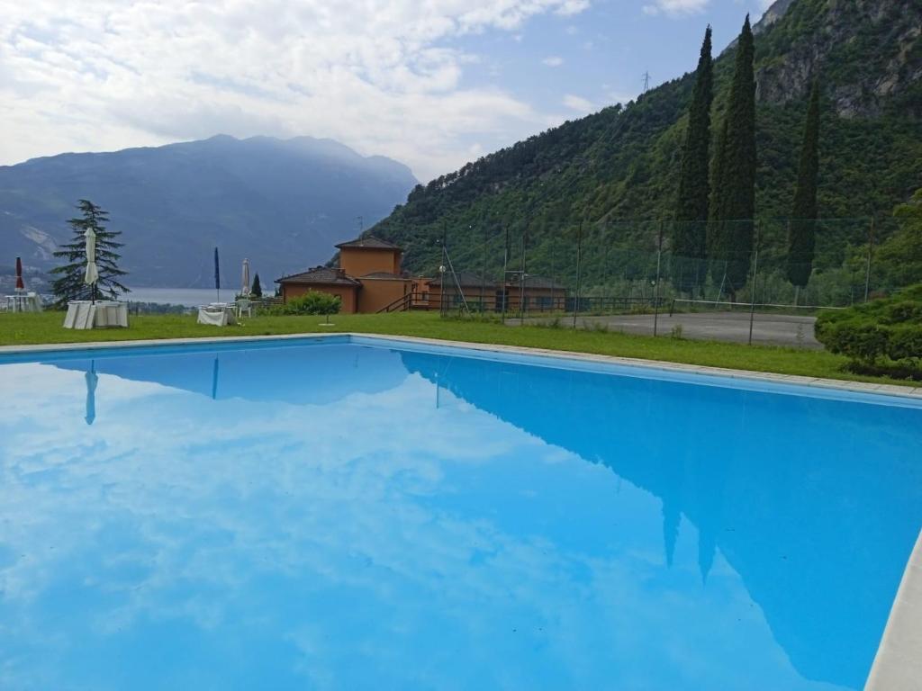 a large blue swimming pool with mountains in the background at L'angolo di pace e relax del lago di Garda in Riva del Garda