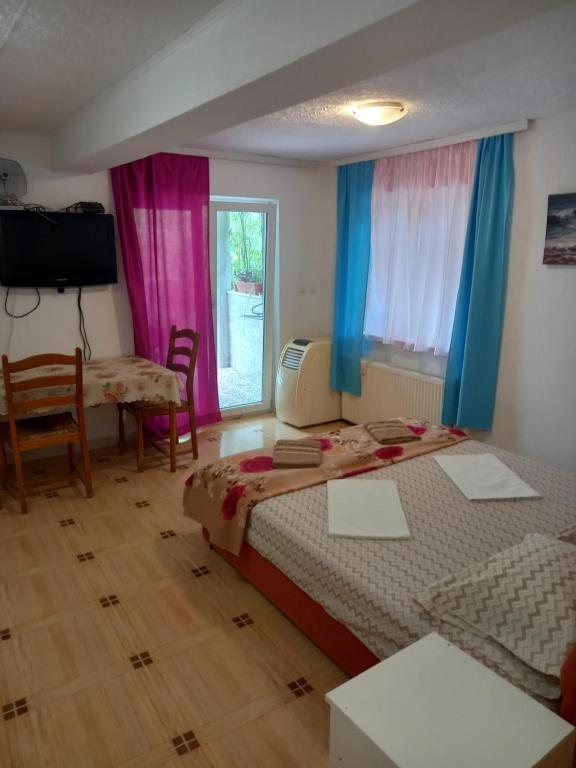 1 Schlafzimmer mit 2 Betten, einem Tisch und einem Fenster in der Unterkunft Bugenvilija in Budva