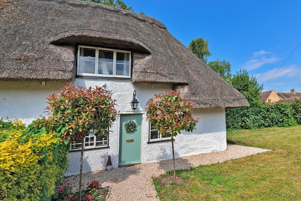 a thatched cottage with a green door and a window at Finest Retreats - Pemberley Cottage 