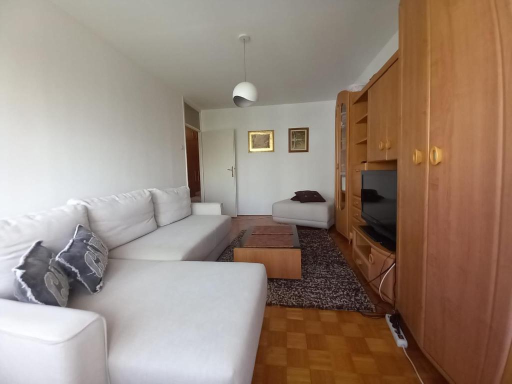 ein Wohnzimmer mit einem weißen Sofa und einem TV in der Unterkunft Cosy apartment Sarajevo in Sarajevo