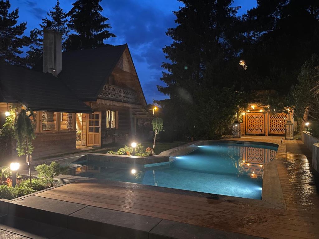 a swimming pool in front of a house at night at Apartamenty Kornaje in Szczawnica