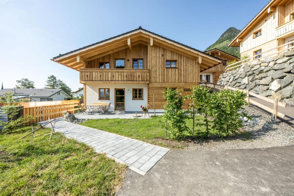 a large wooden house with a stone wall at Waldchalets & Ferienwohnungen Allgäu in Burgberg