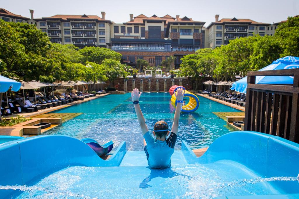 Una mujer en el agua de una piscina de un resort. en The Capital Zimbali, en Ballito