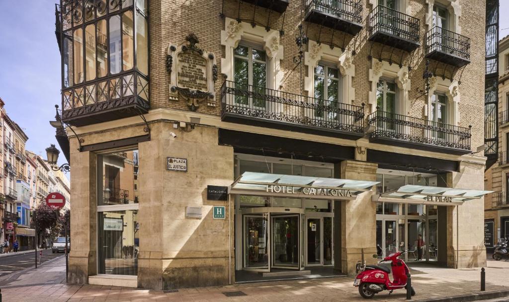 una moto roja estacionada frente a un edificio en Catalonia El Pilar en Zaragoza