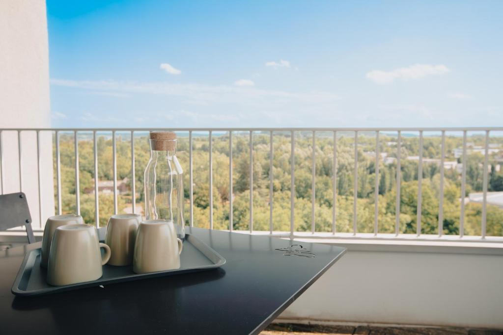 a table with mugs and a bottle on a balcony at Appart' du Trident in Mulhouse