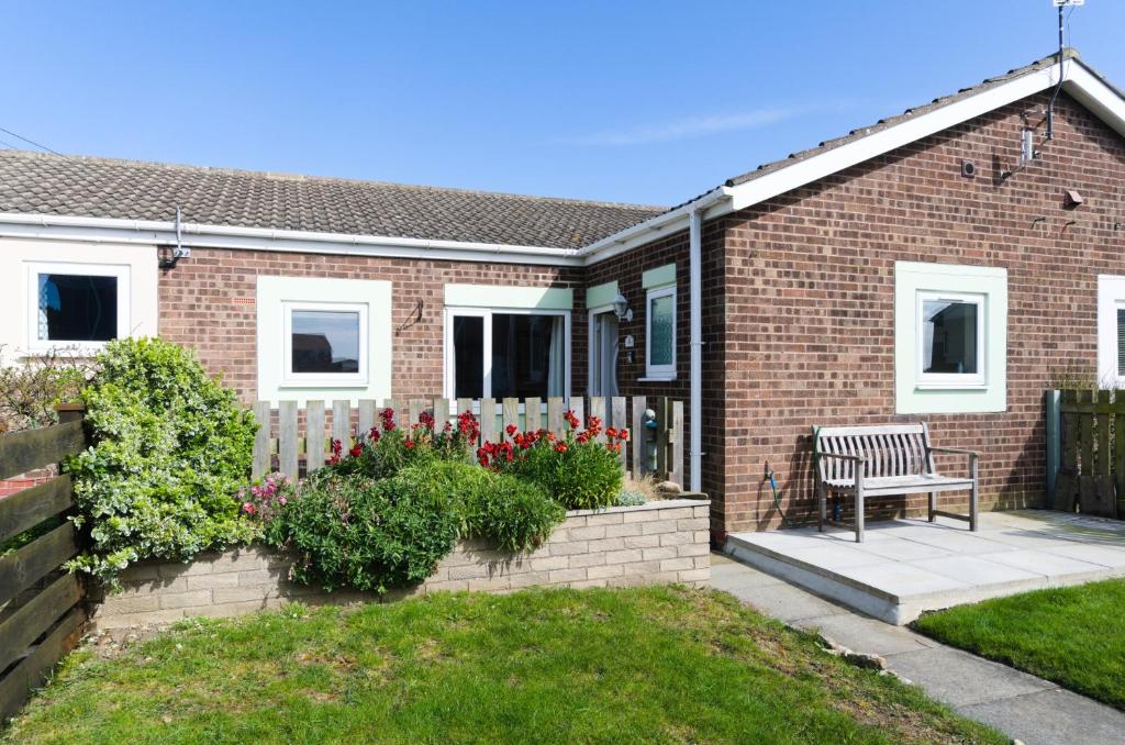 a brick house with a bench in the yard at Rockpool Cottage in Beadnell