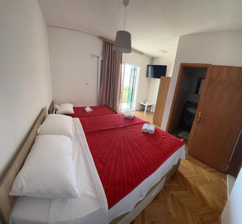 een slaapkamer met een groot bed en een rode deken bij Rooms with shared kitchen "Milica" in Drvenik