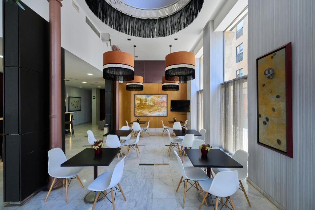 a dining room with black tables and white chairs at Catalonia El Pilar in Zaragoza