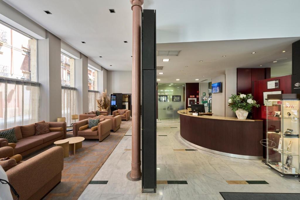 a lobby with couches and a bar in a building at Catalonia El Pilar in Zaragoza