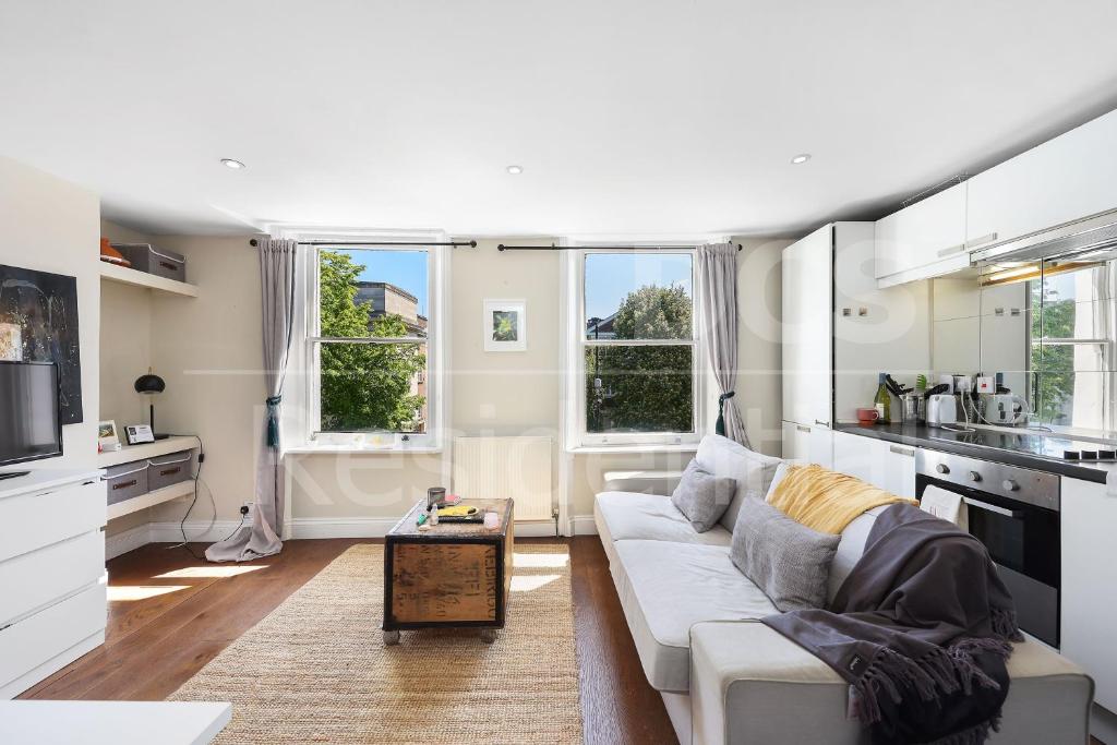 a white living room with a couch and a kitchen at Modernised Apartments 1 and 2 Bedrooms Option Terrace and Balcony High Street in London