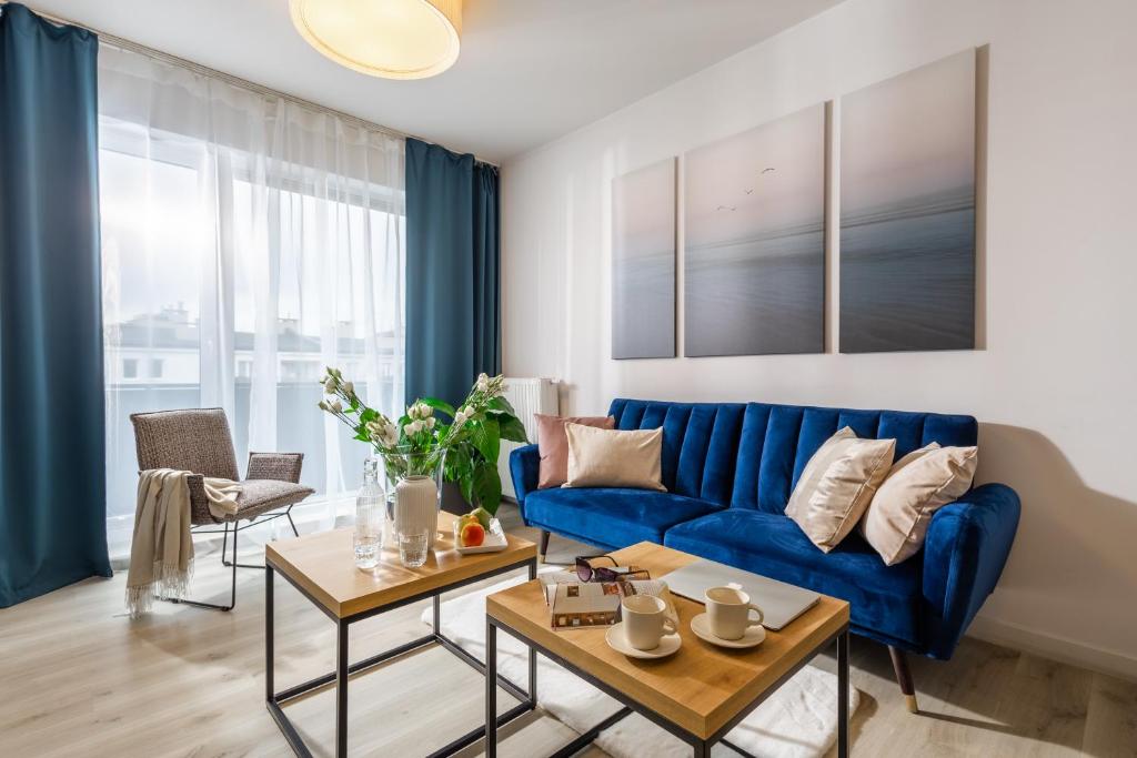 a living room with a blue couch and two tables at Deluxe Apartments by The Railway Station Wroclaw in Wrocław