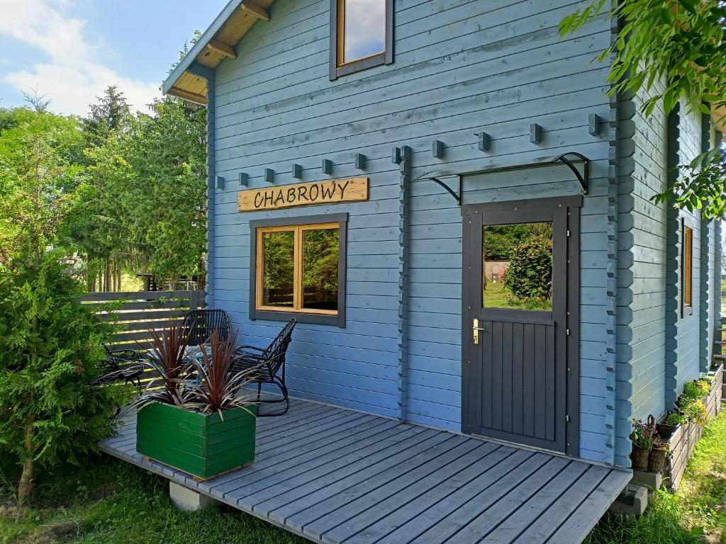 a blue tiny house with a wooden deck at Świerkowe Siedlisko in Węgorzewo