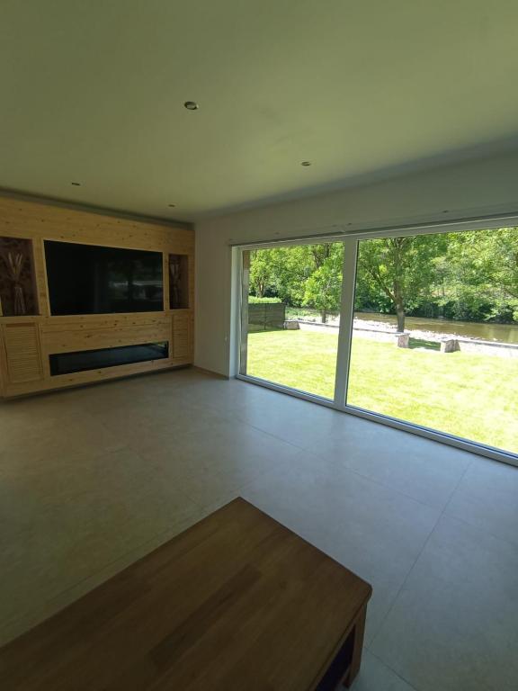 a living room with a large window and a table at La Villa les pieds dans leau in Comblain-au-Pont