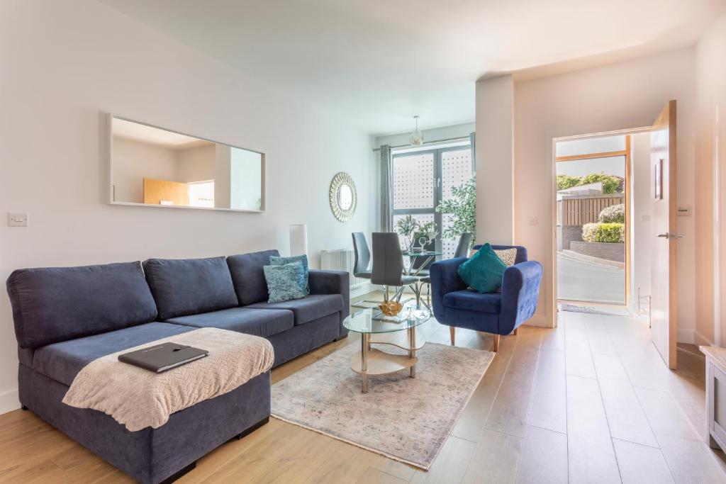 uma sala de estar com um sofá azul e uma cadeira em Belfry Quarters, Redhill em Redhill