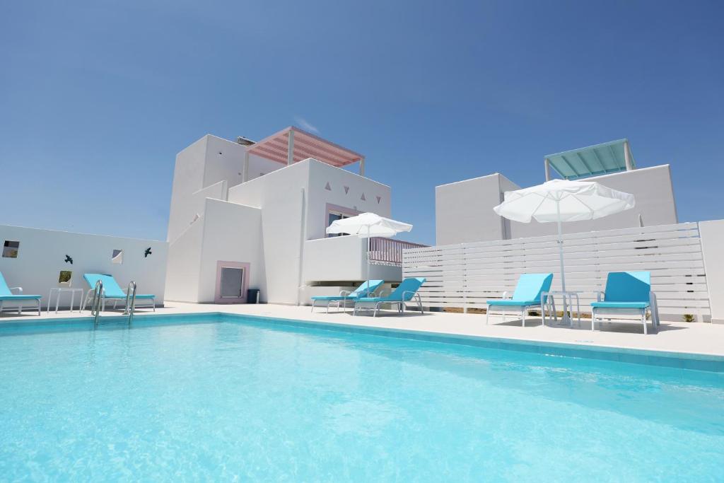 a swimming pool with chairs and umbrellas on a building at Xenos Villa 6 with a Private pool near the sea in Tigaki