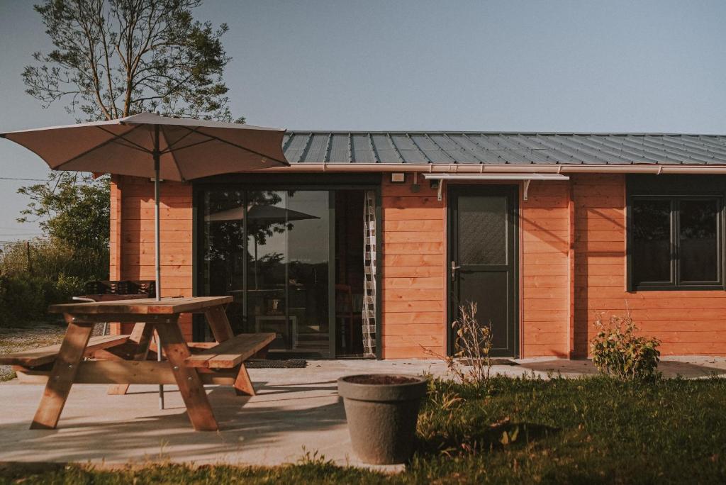 - une table de pique-nique et un parasol en face d'une maison dans l'établissement Chalet 2 chambres parking, à 5 min à pieds d'Etretat, à Bordeaux-Saint-Clair