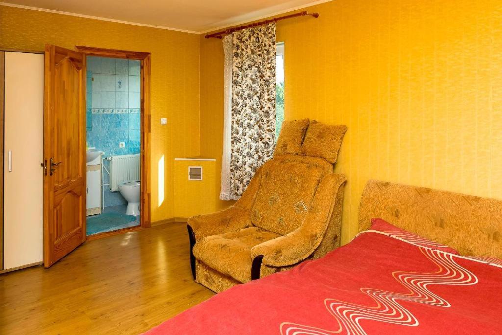 a bedroom with a couch and a chair and a bathroom at Anniņas in Ventspils