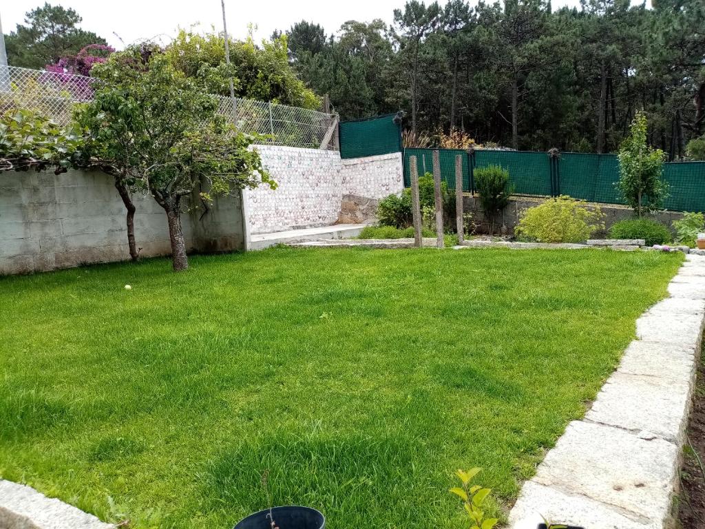 a yard with green grass and a fence at Casa de verano in O Grove