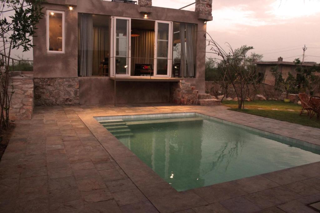 a swimming pool in front of a house at THE BAREWITHIN HOUSE in Jaipur