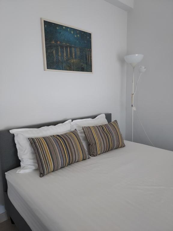1 cama blanca con 2 almohadas y una foto en la pared en Studio Anlia en Nea Makri