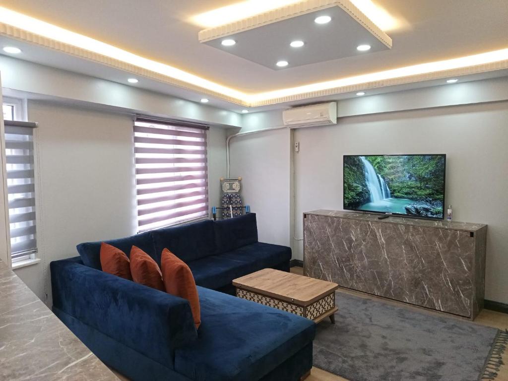 Il comprend un salon doté d'un canapé bleu et d'une télévision à écran plat. dans l'établissement Han Apart, à Istanbul