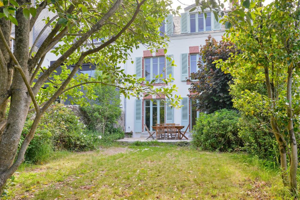 une maison blanche avec un banc dans le jardin dans l'établissement La Maison de Famille - Superbe maison de maître, à Nantes